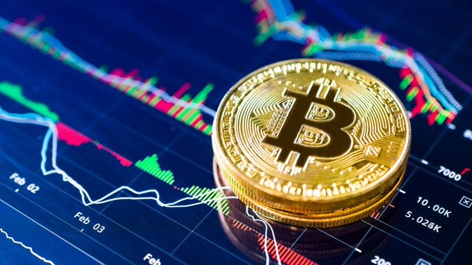 A physical Bitcoin token resting on a screen displaying a colorful price chart.