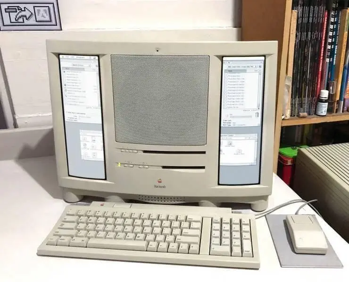 A vintage Macintosh computer setup with an all-in-one beige CRT monitor displaying two application windows, accompanied by a matching keyboard and mouse.