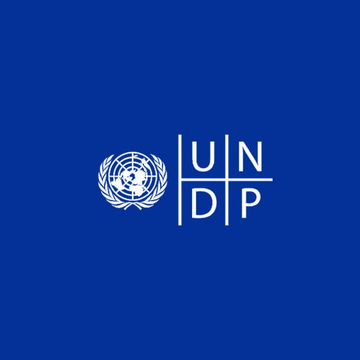 The image displays the UNDP logo (a globe encircled by olive branches alongside the acronym "UNDP") on a dark blue background. It represents the United Nations Development Programme, visually anchoring the announcement that UNDP is extending its blockchain-based payments partnership with Stellar through 2027.