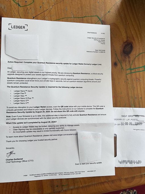 An official-looking letter from Ledger requesting a "Quantum Resistance security update" by August 29, 2026, signed by CTO Charles Guillemet, resting on a wooden surface.