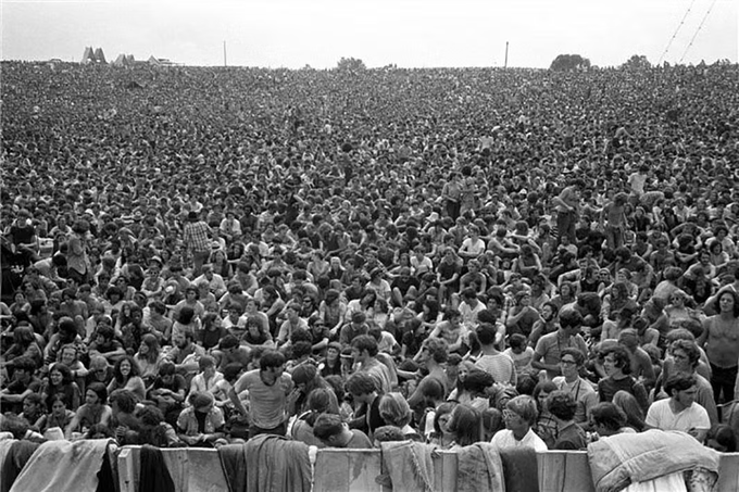 The image shows a large crowd of people gathered together, possibly attending an outdoor event or concert. The crowd consists of both men and women standing close to each other, creating a sense of unity among them. The photo appears to be black and white, which adds a timeless quality to the scene. The caption provided in the image seems to be related to a social media post about a man named "ManifEST" who was at an event on 7 days ago, and another person named "Sol" who attended the same event on today.