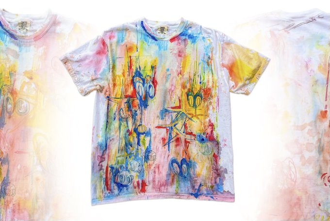 Three pastel-colored tie-dye t-shirts displayed side by side, featuring abstract artwork with cartoon-like figures, hearts, and colorful paint splatter designs.