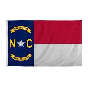 The image shows the North Carolina state flag, featuring its distinctive design with a blue vertical stripe containing a white star, the letters "N" and "C," and two yellow banners reading "MAY 20TH 1775" and "APRIL 12TH 1776," alongside horizontal red and white stripes. This flag represents North Carolina, the state whose new budget is discussed in the accompanying text regarding taxation of prediction markets and sports betting.