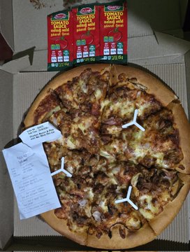 The image features a pizza with various toppings, including pepperoni and sausage, sitting inside an open box. The pizza appears to be freshly baked and ready to eat. Next to the pizza box are two small packages of tomato sauce and cheese, likely meant for use in the pizza-making process. A receipt is also present next to the pizza box, suggesting that someone has purchased this pizza as a treat or reward for their hard work. The image seems to be related to a post on social media, possibly encouraging people to share their own homemade pizzas and receive appreciation from others who enjoy them.