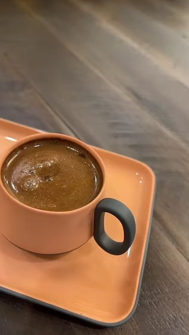 A steaming cup of fresh espresso, served on a vibrant orange saucer, sits on a wooden table—perfectly capturing a cozy "Good morning, CT" vibe for fellow coffee lovers.