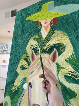 An artist working on a painting depicting a figure in flowing green and white robes wearing a wide-brimmed green hat with red earrings, while painting the mane of a white horse.
