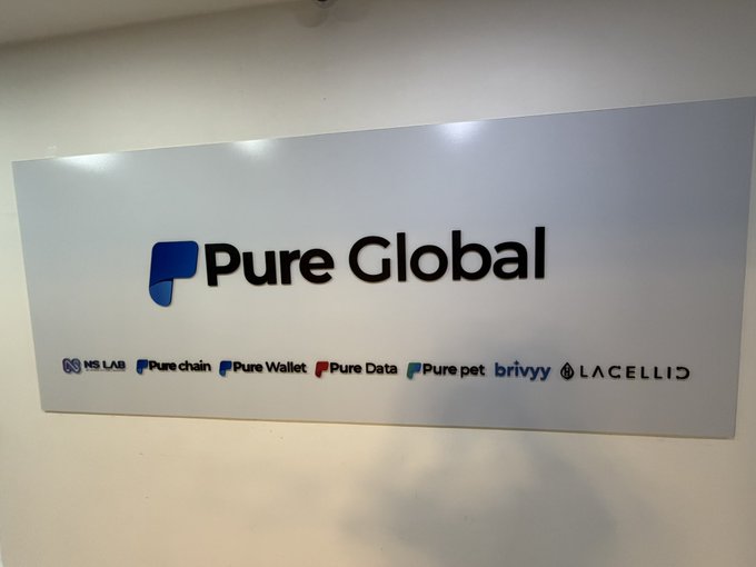The image shows a large white sign with black text that says "Pure Global" above a list of companies including "HSLabs", "HSLabs Pure Wallet", "HSLabs Pure Data", "HSLabs H2 O2 Q3", and "HSLabs H2 O2 Q3". The sign is mounted on the wall, possibly in an office or a store. The image also contains some text that reads: "What is Glam Amsterdam? Ethereum's Next Big Upgrade Explained (Part 1/2) By @ LarryPureLabs Ethereum is gearing up for Glam Amsterdam — its major protocol upgrade targeted for H2 O2 Q3".