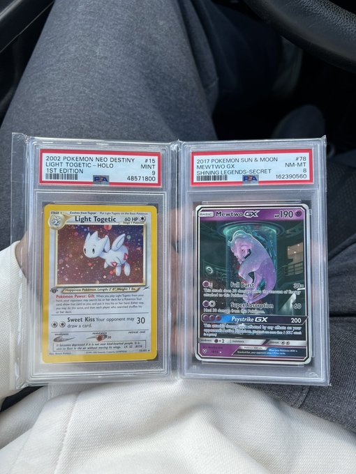 Two PSA-graded Pokémon cards held in plastic slabs, including a 2002 Light Togetic (PSA 9) and a 2017 Mewtwo GX (PSA 9).