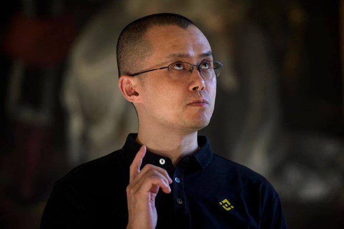 An Asian man with glasses, wearing a black polo shirt with a small yellow logo, gestures thoughtfully while looking upward against a blurred dark background. The image appears to portray a crypto trader referenced in the post as having foresightedly bought the $LAB token at its bottom and sold at the peak for massive profit.