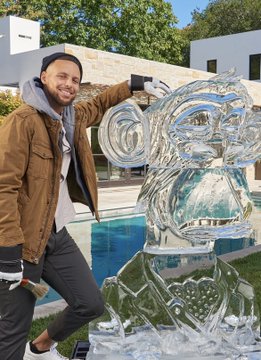 The image features a man standing next to an ice sculpture, which appears to be a monkey made out of ice. The man is wearing a brown jacket and has his arm up towards the ice monkey. In the background, there are two pools with one being larger than the other. A caption on the image reads "BAYC member Steph Curry probably saw that there has been a new wave of BAYC members coming in from China... so he decided to sign with Li-Ning".