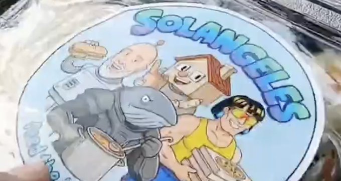 The image features a cartoon-style sticker with a group of cartoon characters, including a shark, holding plates of food and water. The text "solangeels" is written below the characters, indicating that they are part of a community or organization called Solangeels. The post also mentions that Solangeels helped deliver food and water to people in Indonesia during a crisis.