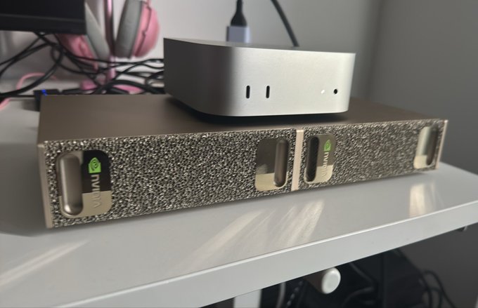A silver Mac Mini sits atop its original textured cardboard packaging box, with "mini" branding visible in green on the box's handle cutouts. The setup appears to be part of a personal tech collection, reflecting the owner's pride and affection for their Apple devices.