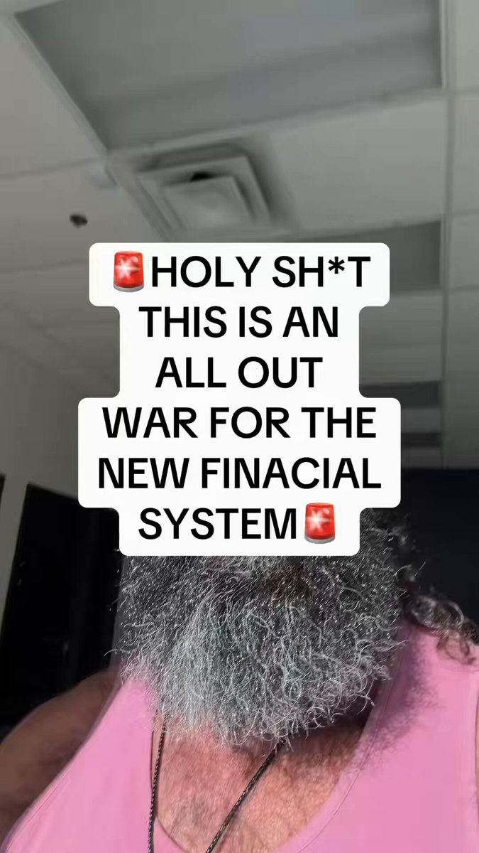 The image features an older man with a long beard wearing a pink tank top, who has taken a selfie using his phone's camera. The caption of the photo reads "HOLY SH*T! This is turning into an all-out battle for control of the future financial system. The old system is being challenged like never before, and the race toward a new era of finance is accelerating. Stay informed. Stay prepared." The man appears to be wearing a necklace around his neck.