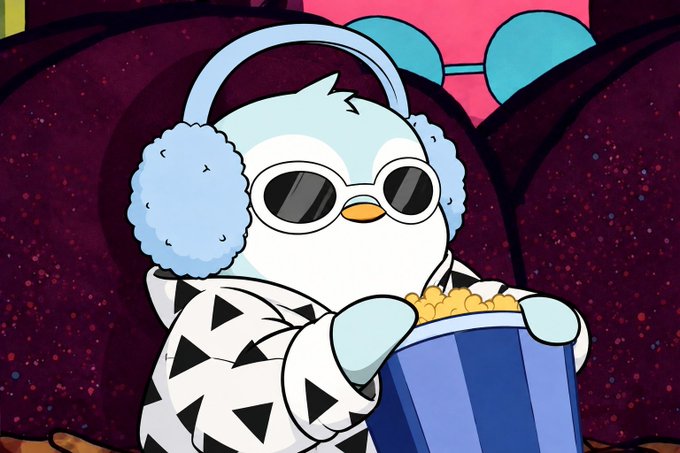 An animated character, a white penguin-like creature wearing sunglasses, fluffy light blue earmuffs, and a black and white triangle-patterned sweater, holding a bucket of popcorn in a dark theater setting.