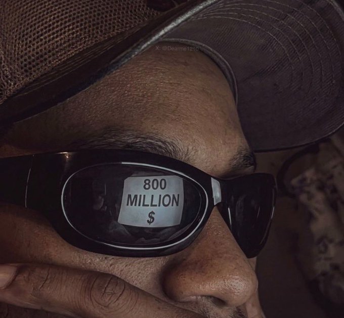 A close-up of a person's sunglasses reflects the words "800 MILLION $" while they adjust their frames, symbolizing a massive target or valuation. The image pairs with the caption "It's Monday… Lock in," suggesting a focused, high-stakes mindset aimed at reaching ambitious financial goals.