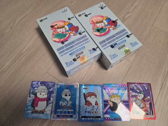 An unopened box of '2024 KNIGHT FACTORY' Pudgy Penguins trading cards alongside several individual holographic cards featuring penguin characters in various poses.