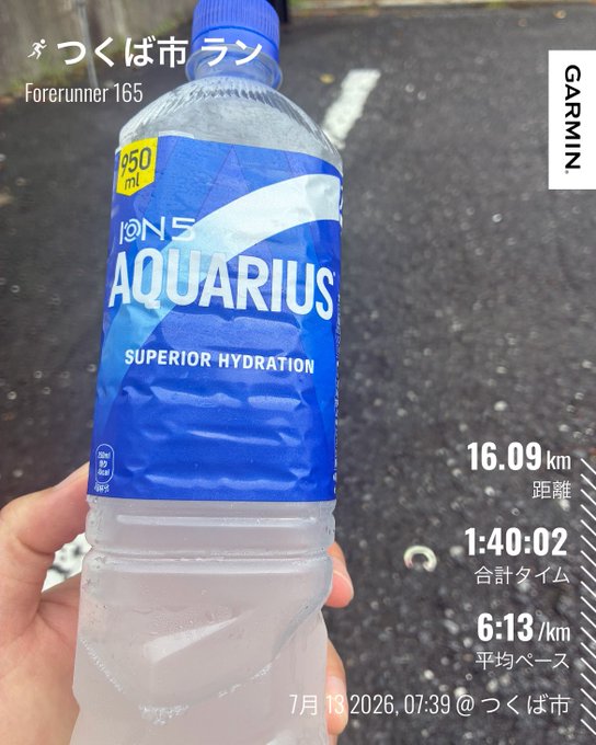 A hand holds an Aquarius sports water bottle against a paved road, overlaid with Garmin Forerunner 165 stats showing a 16.09 km run in Tsukuba City with a time of 1:40:02 and an average pace of 6:13/km on July 13, 2026, fitting the post about an unexpectedly sweaty run on a cool-looking morning.