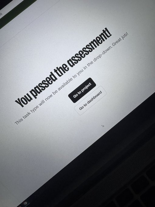 A close-up photo of a laptop screen displaying a confirmation message that reads 'You passed the assessment! This task type will now be available to you in the drop-down. Great job!' with 'Go to project' and 'Go to dashboard' buttons.