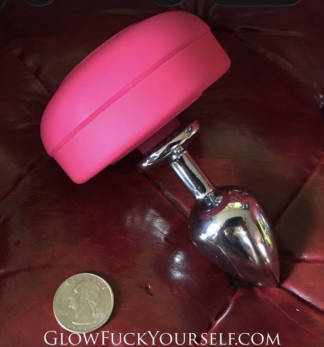 A product photo shows a pink, pill-shaped object next to a silver, phallic-shaped metallic item and a US quarter for scale on a dark red leather surface, with the watermark 'GlowFuckyYourself.com'.
