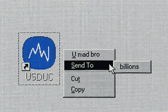 A digital artwork resembling a vintage computer interface showing a blue USDUC logo icon being right-clicked, with a context menu displaying "U mad bro," "Send To," "Cut," and "Copy" options, where "Send To" is expanded to show "billions."