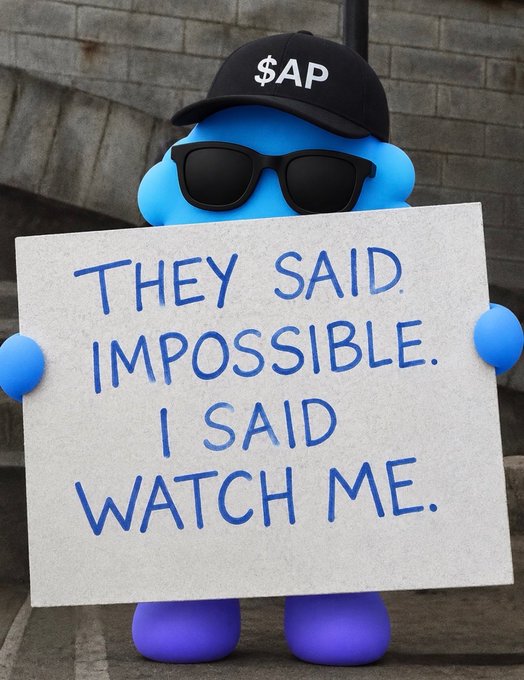 Meme image of a blue character wearing sunglasses and a black '$AP' cap, holding a sign that reads 'THEY SAID IMPOSSIBLE. I SAID WATCH ME.'