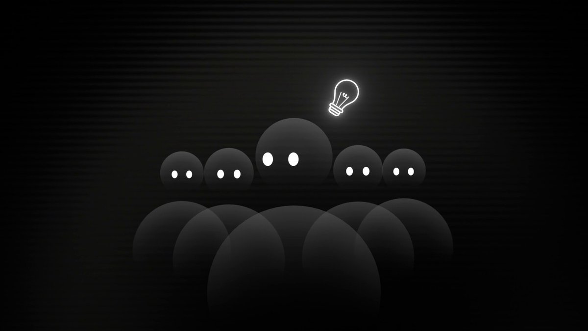 The image features a group of people sitting around each other in a circle, with one person standing out from the rest by holding up a light bulb above their head. The scene appears to be set against a black background, which contrasts with the white elements in the image and makes them stand out even more. The caption provided seems to be related to the image or the post it is associated with, but without further context, it's difficult to determine its exact connection.