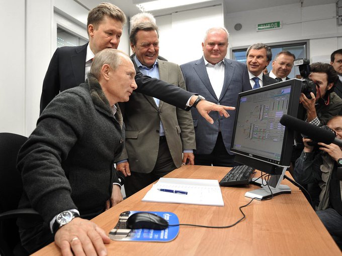 A group of suited men, including Vladimir Putin, gather around a computer monitor displaying technical schematics, while photographers document the moment. The image appears to contrast traditional political leadership with the crypto-forward post declaring Solana ($SOL) as an official federation currency, using the formal setting to humorously frame the meme.