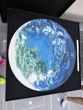 A replica painting of Earth, displayed on a black canvas, sits on a table next to a person's foot. The artwork resembles the style often associated with Jack Ma's famous paintings, referencing the high value piece mentioned in the post.
