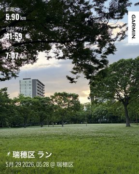 The image shows a park with trees, grass, and buildings in the background. The photo has been captioned with Japanese text that reads "朝ラン5キロ‍ 鼻緒なしワラーチで走ってみました 反発ゼロで最初はびっくり、一歩ずつ丁寧に走るのが新鮮これから暑くなるのでゆるいジョグの時は台湾サンダルかワラーチで走ります". The caption is in Japanese and provides information about the time of day, location, and a description of the scene.