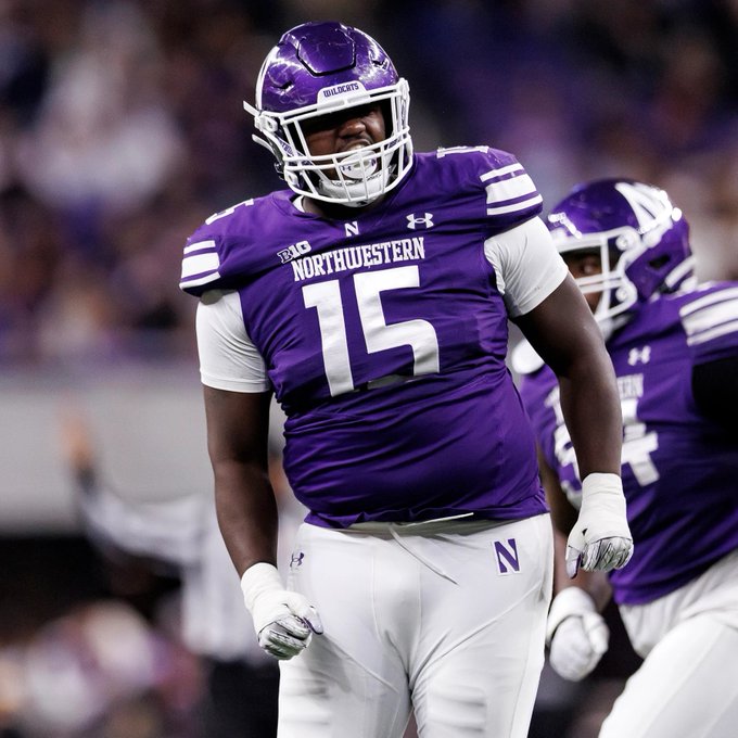 A Northwestern University football player wearing a purple jersey with the number 15 and a purple helmet, celebrating on the field during a game.