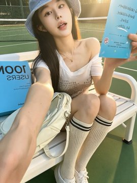 A young woman wearing a white bucket hat, white top, and knee-high socks takes a selfie on a bench while holding a blue sign with partially visible text.