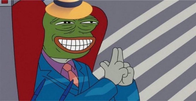 A cartoon image of a green-skinned character in a blue suit and small hat grinning widely while making a peace sign with his hand.
