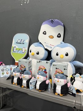 A display of penguin plush toys and merchandise on a store shelf.