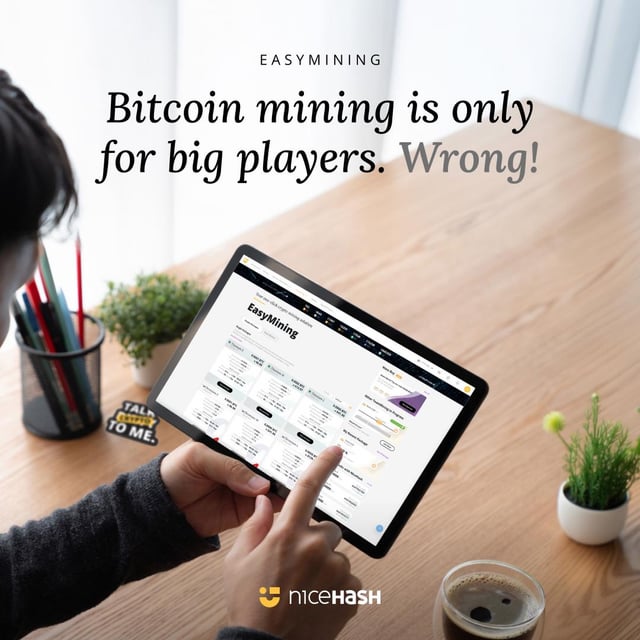 The image shows a person using a tablet computer, likely browsing or researching Bitcoin mining. The text above the tablet reads "Easy Mining" and "BitCoin mining is only for big players. Wrong!" This statement suggests that Bitcoin mining might be exclusive to large-scale miners due to its high energy consumption and cost, which can deter smaller miners from participating in the activity.

The image also includes a potted plant on a table next to the person using the tablet, as well as other objects like cups and pens. The overall scene conveys an atmosphere of casual work or leisure time spent with technology and Bitcoin mining.
