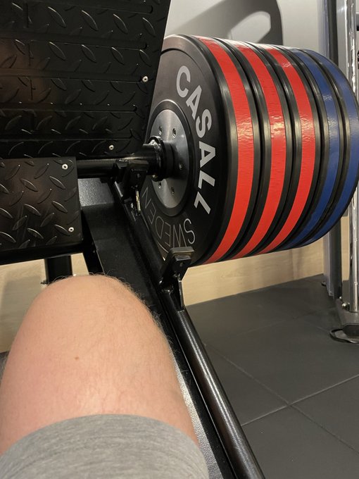 A first-person view from a leg press machine shows a heavy stack of plates branded "CASAL SWEDEN" loaded with red, black, and blue weights, as the user reminds followers to hit the gym or risk Peter Parker stepping in.