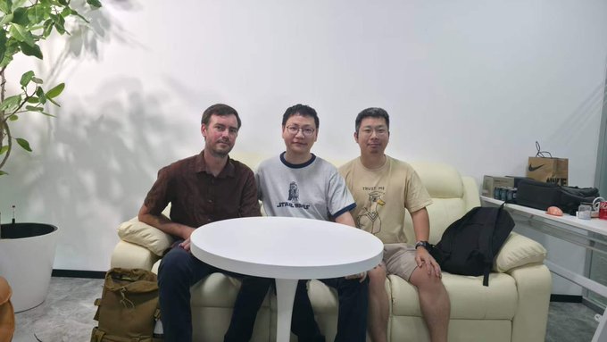 Three men pose together on a white couch around a small round table, appearing relaxed and engaged in conversation. The setting suggests a casual yet productive meeting space, complementing the post's enthusiasm about a recent discussion on the Neo ecosystem and its future developments.