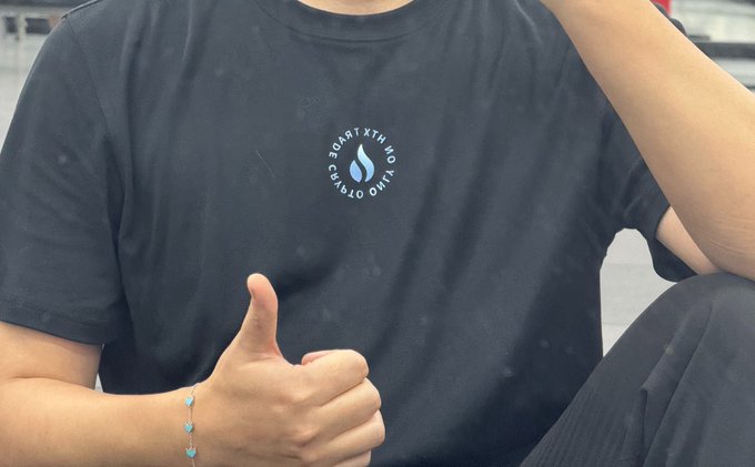 A person wearing a black T-shirt with an OnlyFans logo and the text 'ONLY FANS THE SAFE SPACE' gives a thumbs-up gesture while wearing a beaded bracelet.