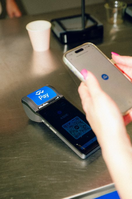 A customer uses their smartphone to scan a QR code on a payment terminal for a transaction of 4.50€. This image relates to the post by visually representing the cashback system where WCT were distributed during the coffee campaign.