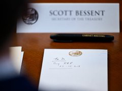 A handwritten note rests on a desk in front of a nameplate reading "SCOTT BESSENT, SECRETARY OF THE TREASURY," alongside a pen, while a blurred figure in a suit appears in the foreground. The image appears to depict an official meeting or correspondence connected to financial policy matters, visually reinforcing the post's claim about institutional developments potentially involving XRP and the CLARITY Act.