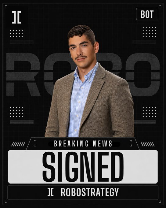 The image features a man standing against a black background, wearing a suit and tie. The man is being photographed and has his name displayed below him that reads "Robots". Next to him, there are words such as "BREAKING NEW REPORTS", "SIGNED", "@JII ROBBOSTRATEGY", and "@VIRTUALSIO". In the background of the image, a robot is visible. The man's name and position can be inferred from these details in the image, but it does not provide information on his role or involvement with robots.