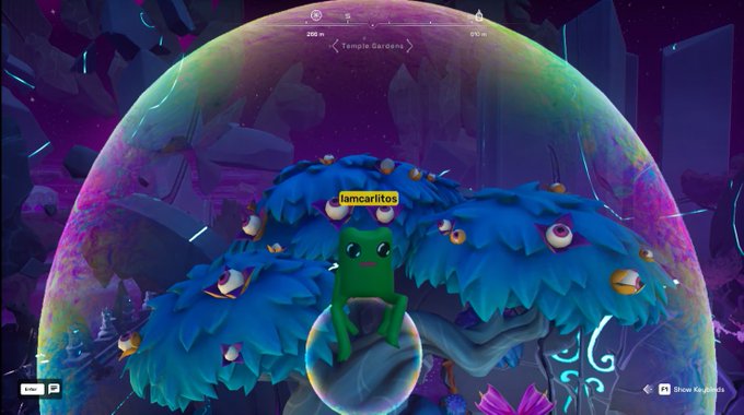 A green frog character named 'lamcarititos' sits on a blue mushroom-like structure within a glowing bubble in a colorful game scene labeled 'Temple Garden'.