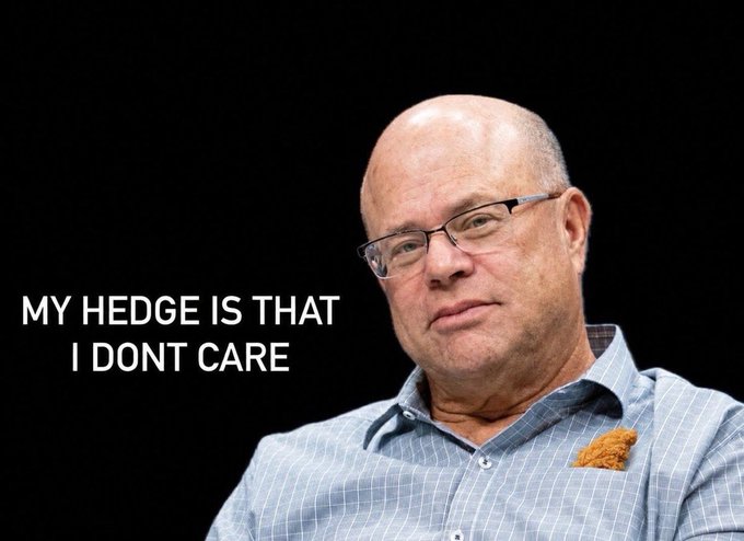 A bald, bespectacled man wearing a blue checkered shirt and an orange pocket square looks unimpressed against a black background, with bold white text reading "MY HEDGE IS THAT I DONT CARE" displayed on the left side. The image pairs with the post to convey a dismissive, unapologetic attitude toward a bullish bet on a cryptocurrency, with the man embodying confidence in the investment decision regardless of outside opinion.