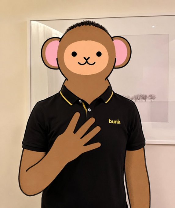 A cartoon monkey mask emoji obscures a person's face as they wear a black polo shirt with yellow trim labeled 'bunk' and place a hand on their chest.