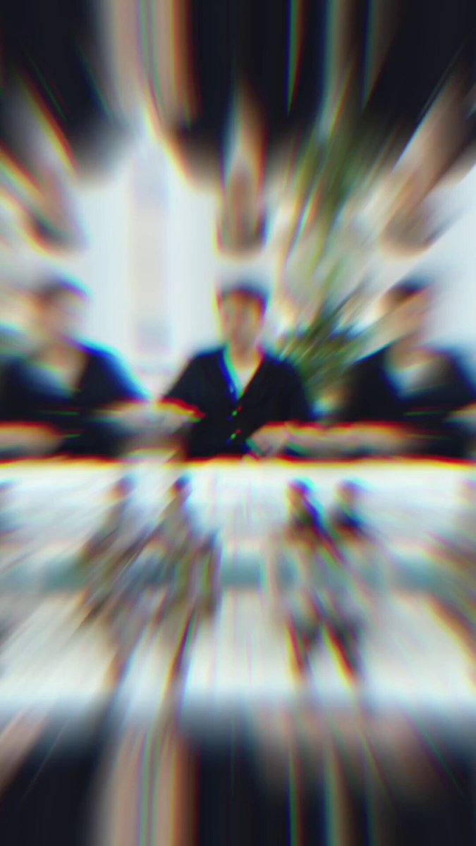 The image shows a blurry photo of people sitting around a table, possibly engaged in conversation or working together. The focus of the image is on the blurred faces of the individuals present at the table. The background appears to be a room with a window that allows natural light into the space. There are no discernible texts or specific objects within the frame, and the relative positions of the people around the table seem to be indistinct due to the blurriness.