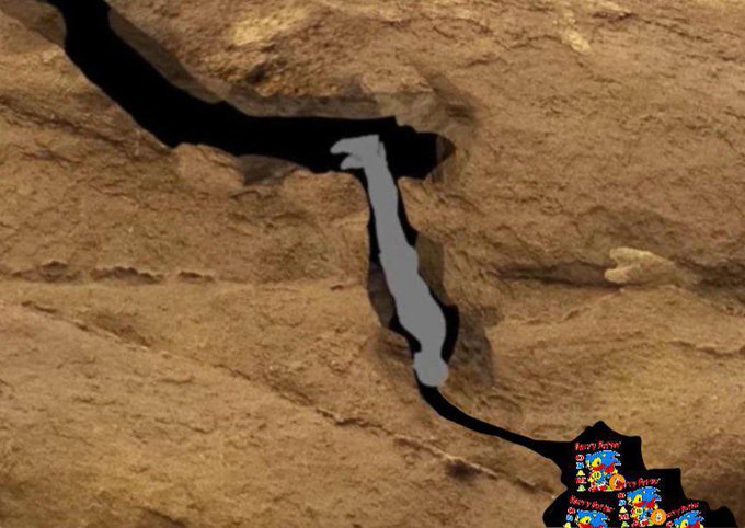 A satellite/aerial view showing a large shadow or dark shape extending across a brown, rocky desert landscape, with colorful character stickers (Merry Marge, Berry Burst) overlaid in the bottom right corner.