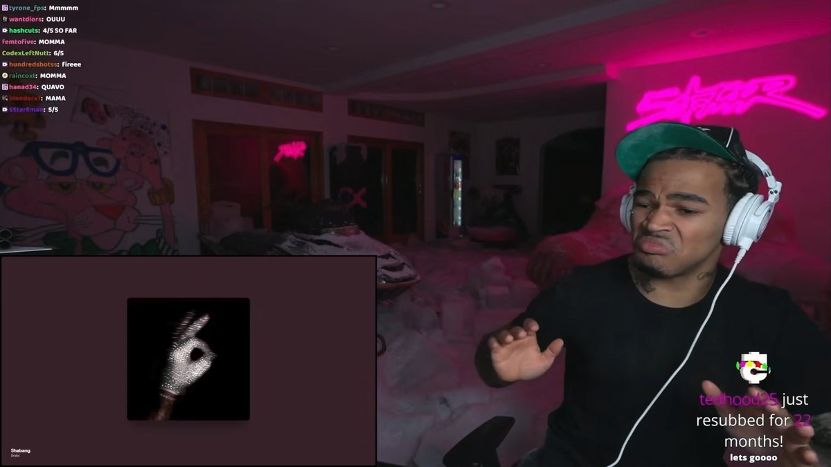 The image shows a man wearing headphones, holding a microphone, and standing in front of a computer screen displaying a webpage with text that reads "Beta access to Polymarket Perps is now live". The man appears to be engaged in an online gaming session or streaming activity related to the game.

The room has pink walls and a pink neon sign on the wall, creating a vibrant atmosphere for the gaming experience. There are also other people visible in the image, suggesting that this might be a multiplayer gaming event or a live stream where multiple players can participate simultaneously.