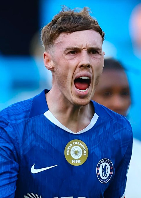 A close-up photo of Chelsea football player Cole Palmer in a blue jersey with the FIFA Club World Champions badge, shouting on the field.