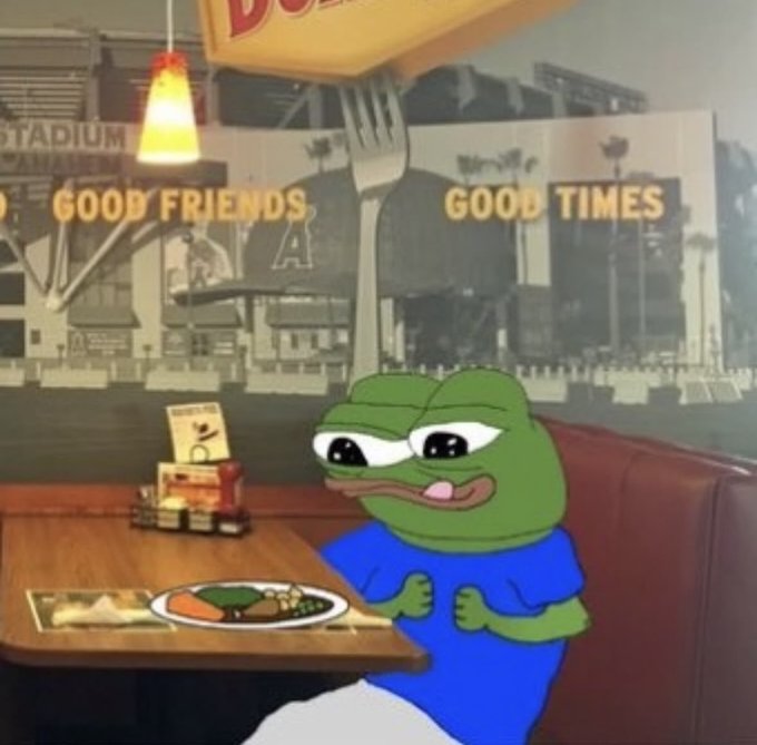Image of Pepe the Frog sitting in a diner booth with 'GOOD FRIENDS GOOD TIMES' signage visible in the background.