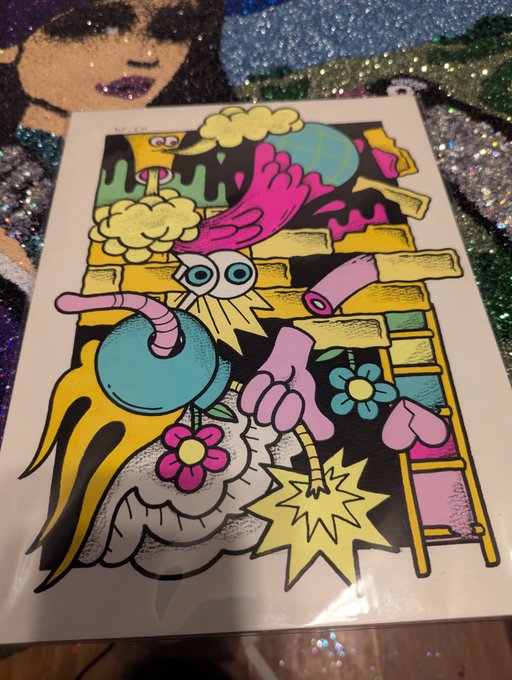 A vibrant, colorful pop-art style poster features a cartoonish pink bird-like creature with large eyes and a flaming bomb, surrounded by flowers, a ladder, and pink dripping elements on a black background.