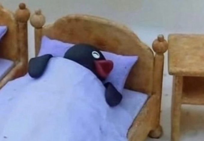 A close-up shot shows a penguin plush toy tucked into a small wooden bed under a purple blanket.